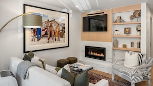 A modern living room with a fireplace, a mounted TV, and a large framed picture.