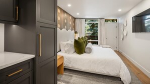 A modern bedroom with a large bed, a nightstand, a wardrobe, and a window with curtains.