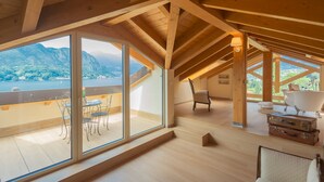 A spacious room with large windows offering a mountain view, wooden beams on the ceiling, and a cozy seating area with a bathtub and luggage. - Villa Cosima in Bellagio With Private Pool (Bellagio)