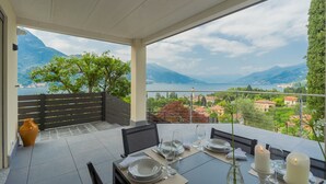 A terrace with a table set for dining, overlooking a mountainous landscape and a body of water. - Villa Cosima in Bellagio With Private Pool (Bellagio)