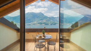 A balcony with a table and chairs, overlooking a lake and mountains. - Villa Cosima in Bellagio With Private Pool (Bellagio)