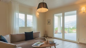 A modern living room with a sofa, a coffee table, and a view of mountains through large windows. - Villa Cosima in Bellagio With Private Pool (Bellagio)