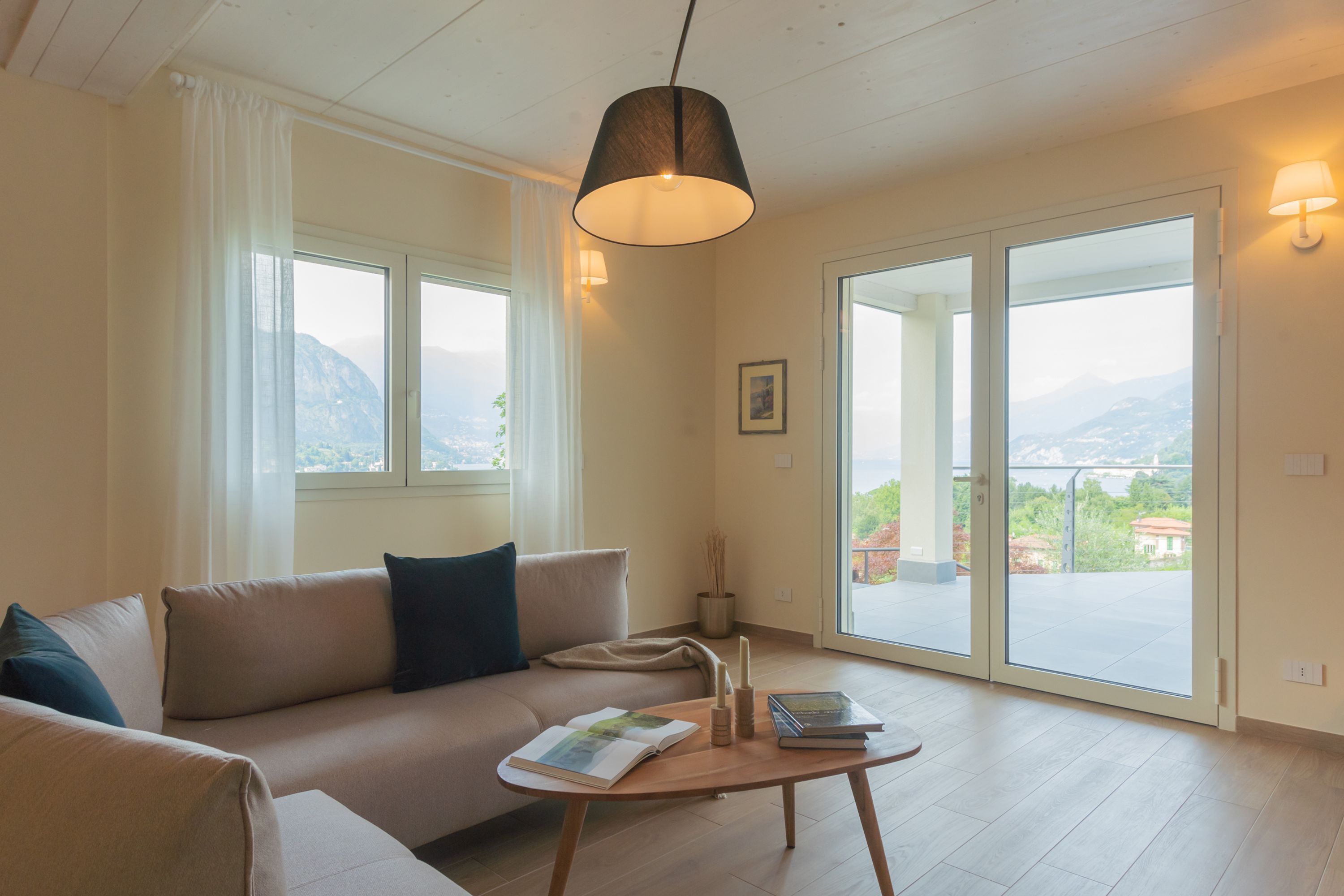 A modern living room with a sofa, a coffee table, and a view of mountains through large windows.