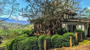 A rustic cabin with a wooden exterior, surrounded by well-maintained hedges and a fenced area.
