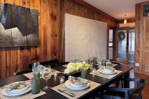 Une table à manger dressée avec des assiettes, des verres et un centre de table composé de fleurs.