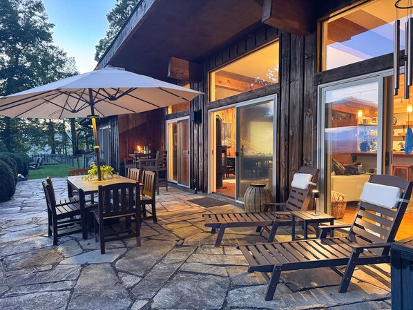 A stone patio with outdoor furniture, a table with chairs, and a large umbrella.