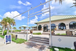 A bistro with outdoor seating, a covered patio, and a staircase leading to the entrance.