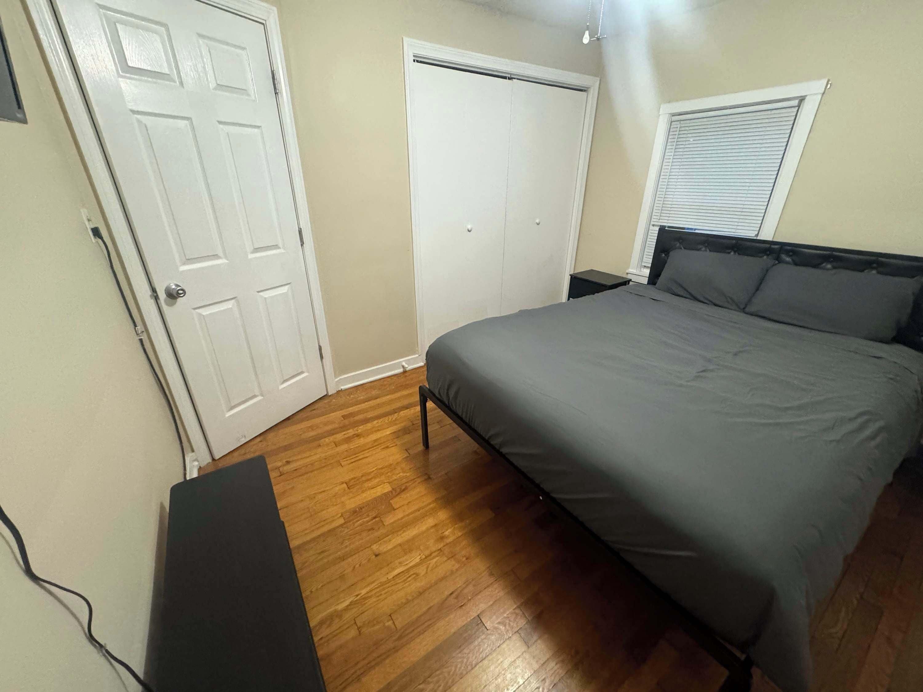 Un dormitorio con cama, puerta, armario y ventana.