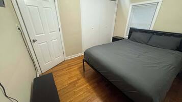 Un dormitorio con cama, puerta, armario y ventana.