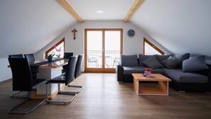 A modern loft apartment with a dining area, a sofa, and a small table. - PJ Apartments & Wellness - Hot Tub & Sauna - Free Parking (Cerklje na Gorenjskem)