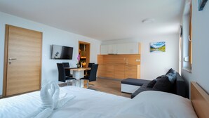 A modern hotel room with a large bed, a desk with a chair, a kitchenette, and a TV. - PJ Apartments & Wellness - Hot Tub & Sauna - Free Parking (Cerklje na Gorenjskem)
