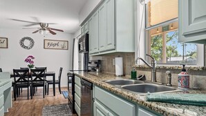 A kitchen with granite countertops, a dishwasher, a sink, and a ceiling fan.