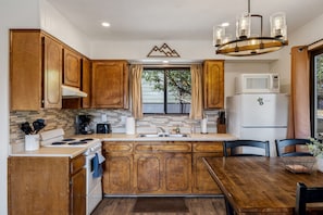 A kitchen with wooden cabinets, a stove, a microwave, and a dining area with chairs. - Mountain Vista (Greer)