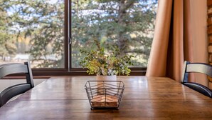 Een eettafel met stoelen, een potplant en een raam met gordijnen.