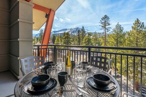 Un balcon avec une table dressée pour le dîner, offrant une vue sur un paysage montagneux.