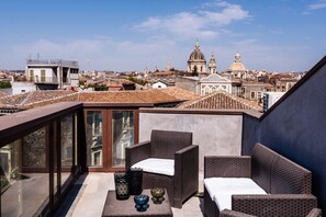 A rooftop terrace with wicker furniture, a glass balustrade, and a cityscape view. - Vecchio Bastione With Terrace by Wonderful Italy (Catania)