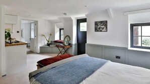 Un dormitorio con cama, ventana, espejo y puerta que da a otra habitación.