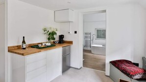 Una cocina compacta con encimera de madera, un refrigerador pequeño y una planta en maceta.