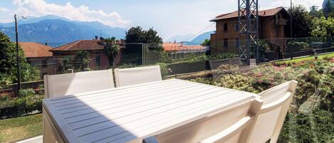 A table and chairs on a balcony with a view of mountains and a power line tower.