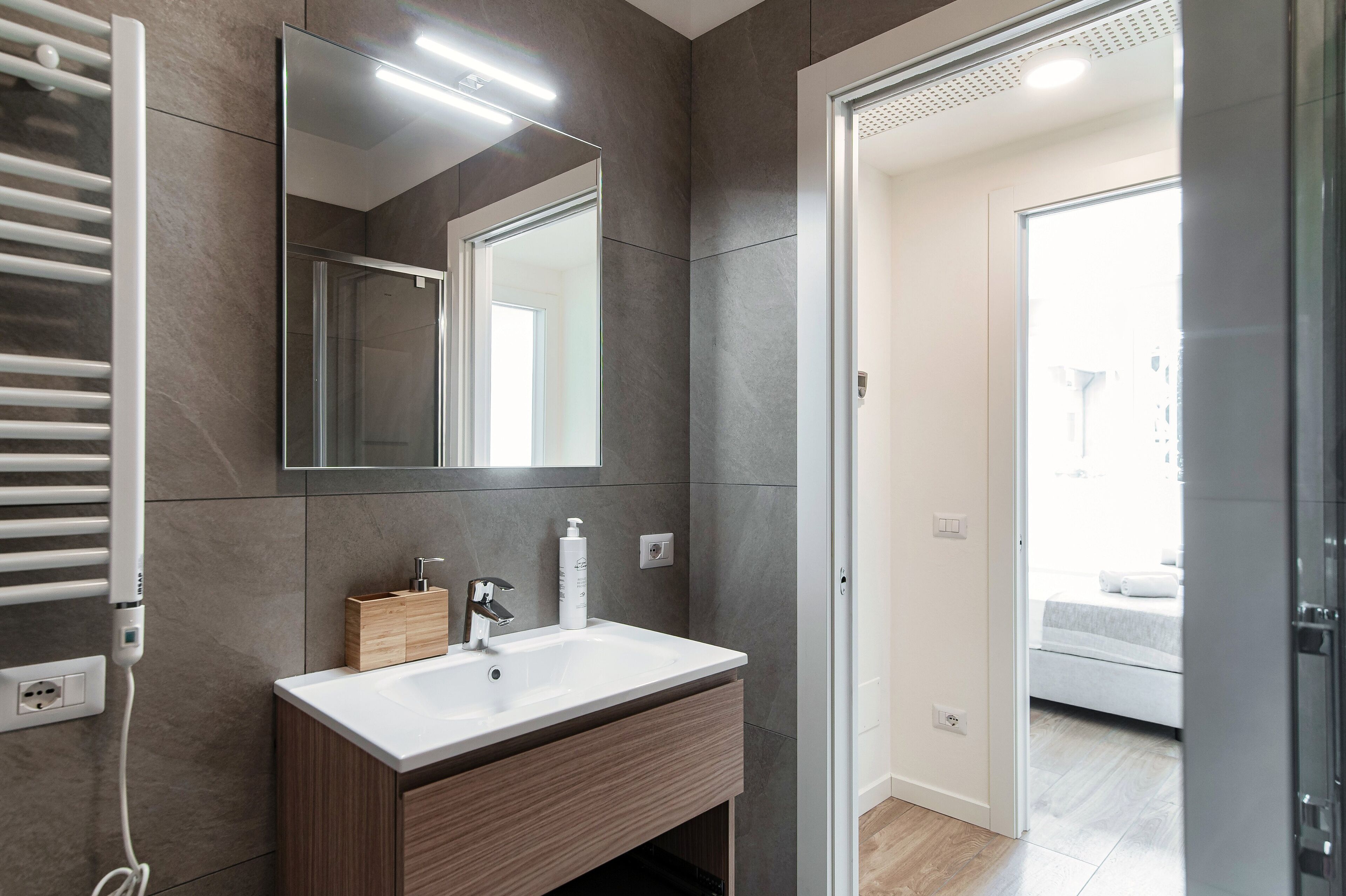 A modern bathroom with a white sink, a mirror, and a towel rack.