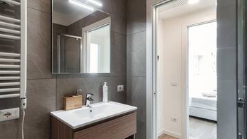 A modern bathroom with a white sink, a mirror, and a towel rack.