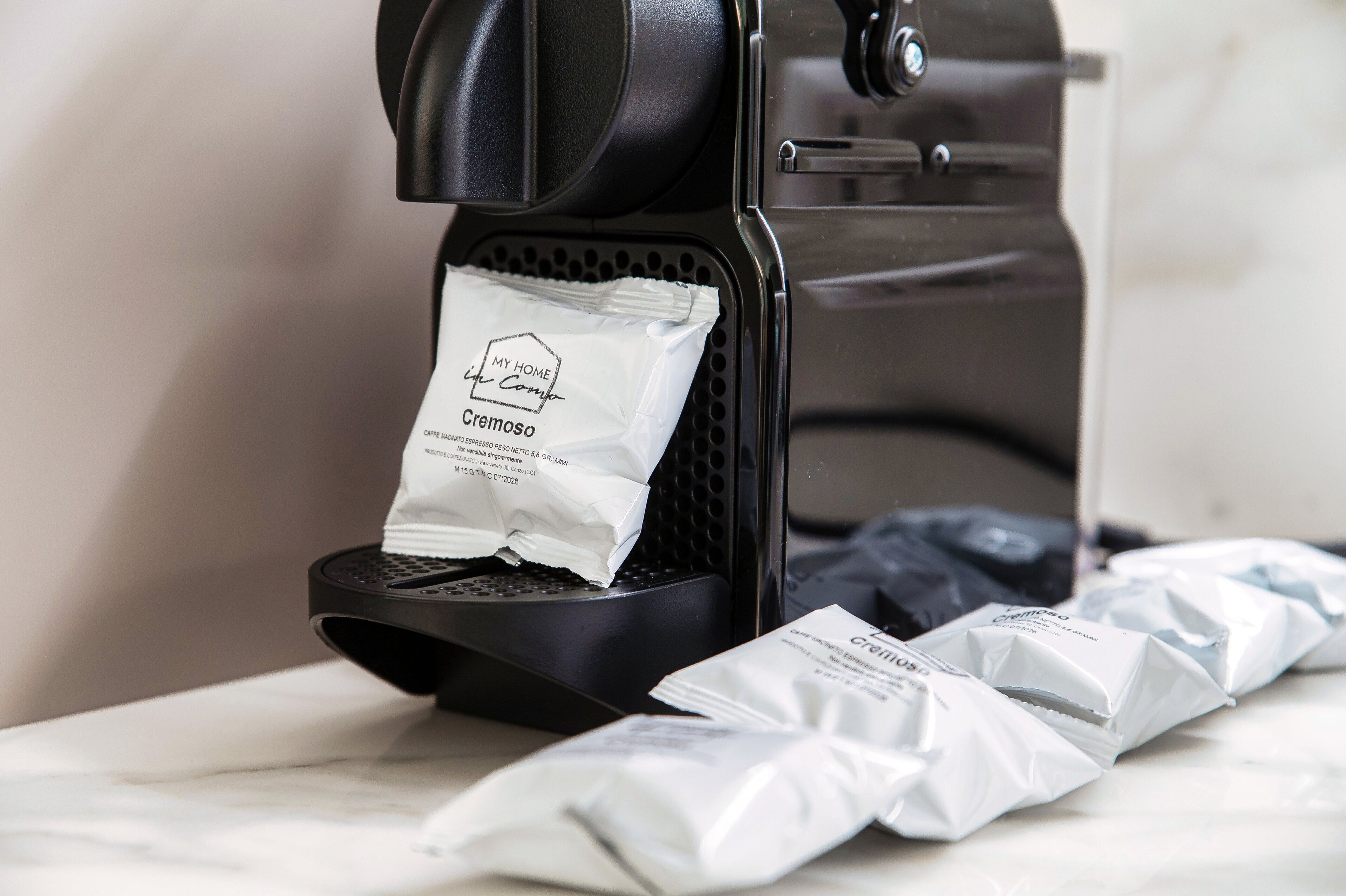 A coffee machine with a coffee pod dispenser and several coffee pods on a marble surface.