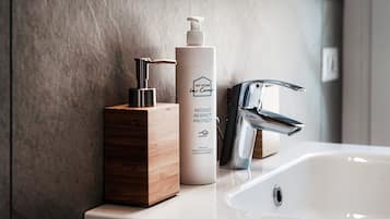 A bathroom with a white sink, a wooden soap dispenser, and a bottle of hand soap.