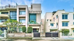 Un moderno edificio residenziale a più piani con ingresso carrabile, balconi e un giardino curato.