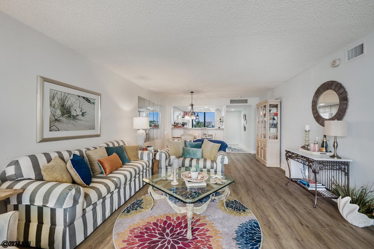 Un salon avec un canapé à rayures, une table basse en verre et un tapis coloré.