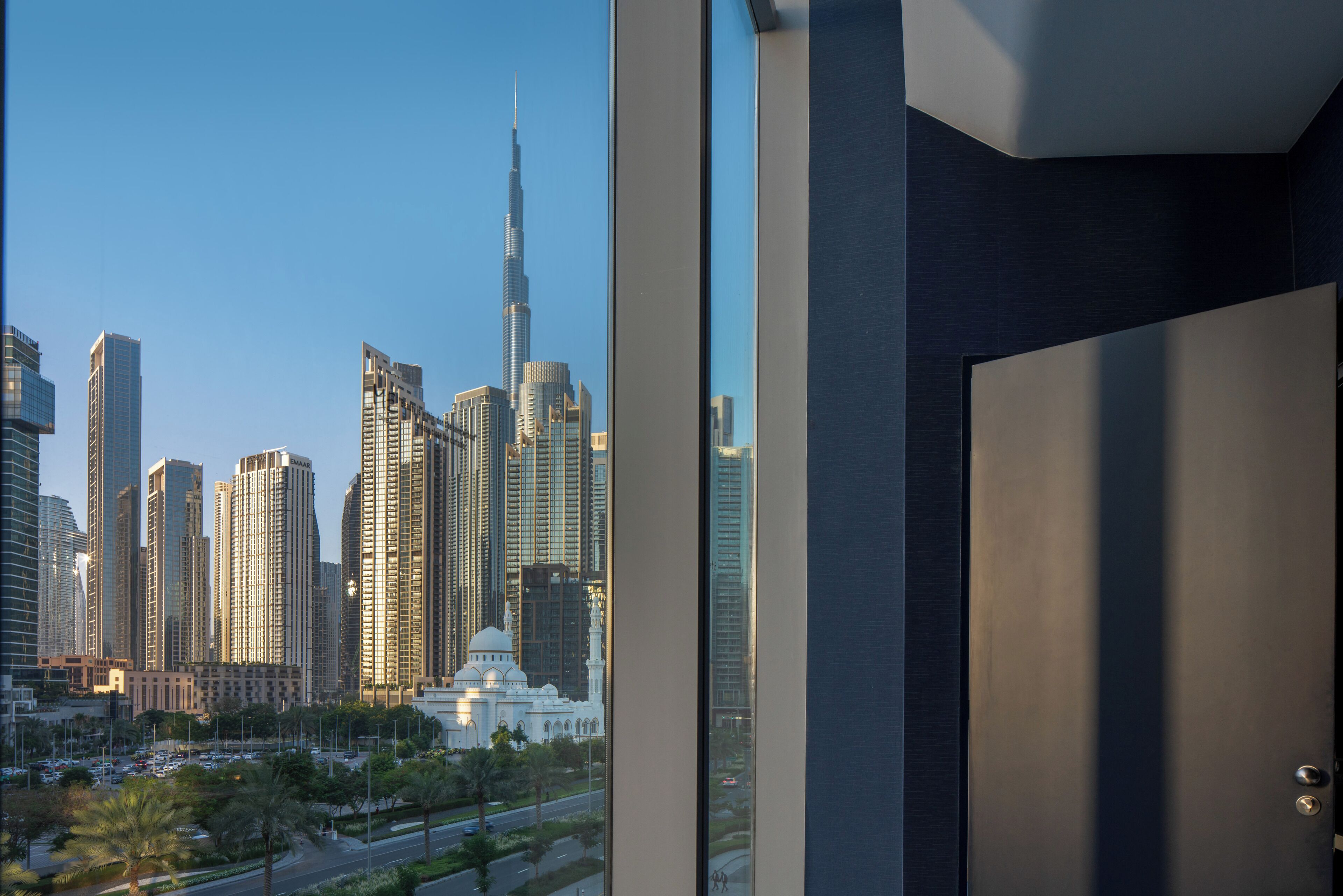 A modern building with a view of a city skyline, including a prominent skyscraper.