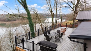A deck with outdoor furniture overlooking a river and a bridge. - Lakeview Lodge • Sleeps 14 • Game Room • Fire Pit (Bronston)