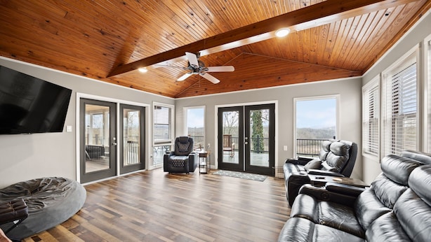 A spacious living room with a wooden ceiling, a ceiling fan, a large leather sofa, a bean bag, and a flat-screen TV mounted on the wall. - Lakeview Lodge • Sleeps 14 • Game Room • Fire Pit (Bronston)