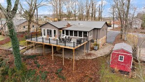 A two-story house with a covered deck and a red barn. - Lakeview Lodge • Sleeps 14 • Game Room • Fire Pit (Bronston)