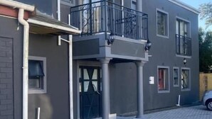 A modern two-story building with a balcony, a garage, and a paved driveway. - Sabathlogde VIP  (Cape Town)