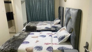 A room with two beds, a wardrobe, and a curtain. - Sabathlogde VIP  (Cape Town)