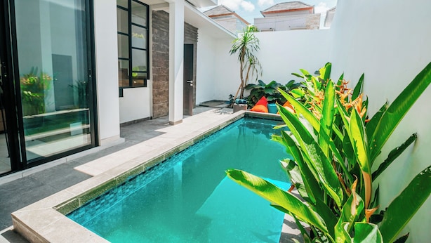 A modern pool area with a clear blue pool, surrounded by a white wall and a glass door leading to a room. - VILLA BALIEM CHRIST (Jimbaran)