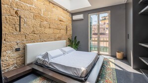 Quarto moderno com parede de pedra, claraboia, cama e vista para o exterior.
