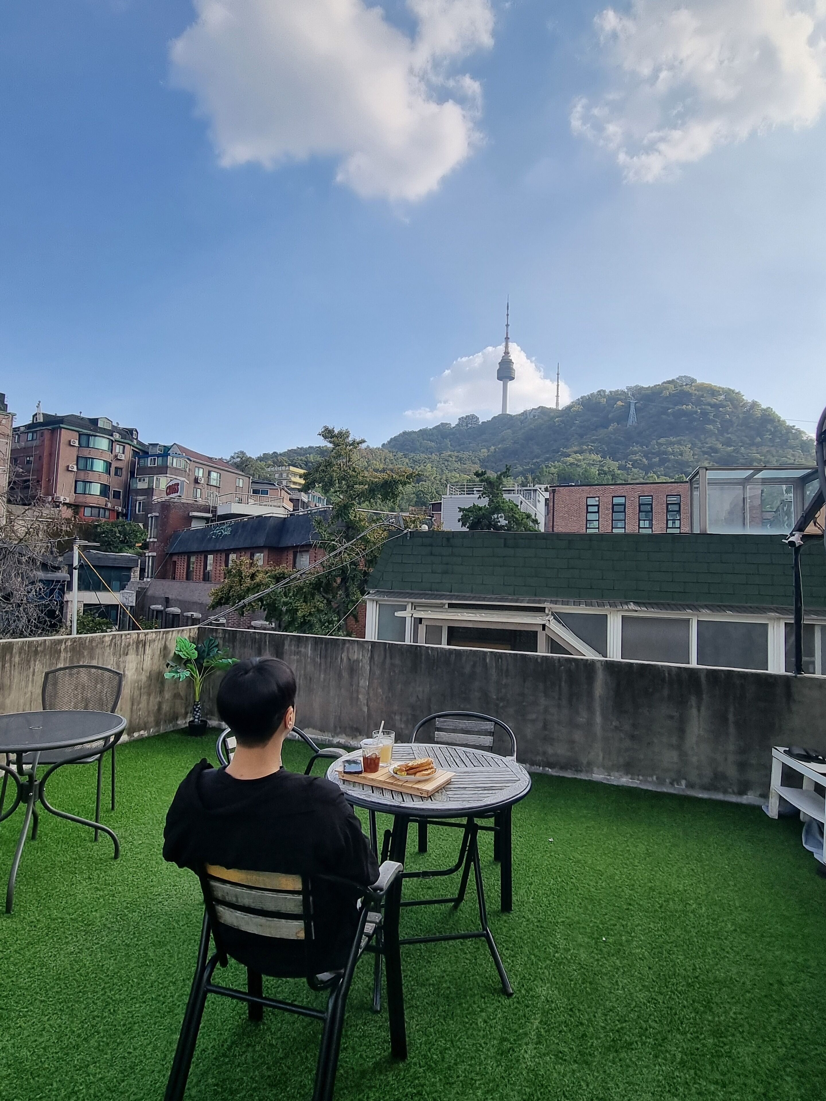 A rooftop terrace with a view of a tower on a hill, surrounded by buildings.