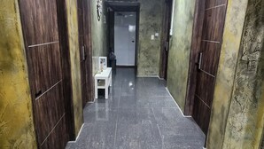 A hallway with dark tiled flooring, wooden doors on both sides, and a small table with a chair in the center. - Space Guesthouse (Seoul)