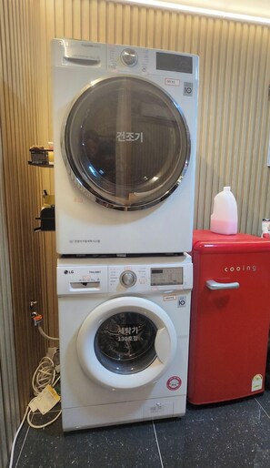 A stacked washer and dryer unit with a red appliance next to it. - Space Guesthouse (Seoul)