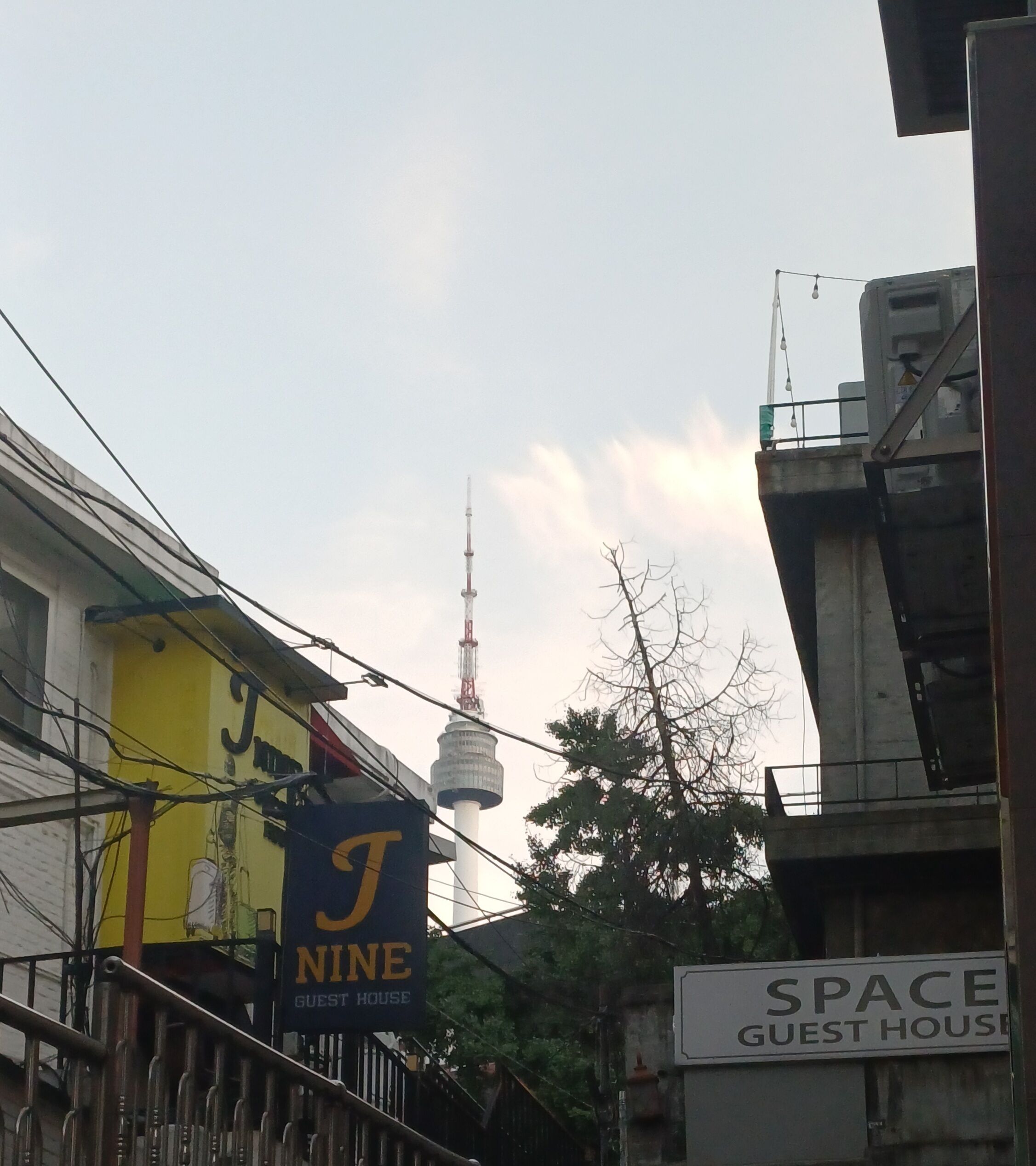 Un edificio con un cartel que dice 'J NINE GUEST HOUSE' y otro cartel que dice 'SPACE GUEST HOUSE' en primer plano.