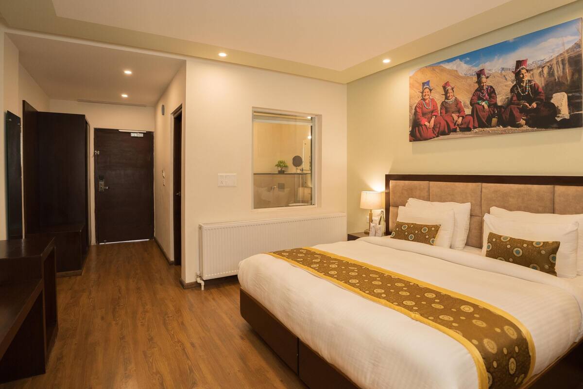 Un cuarto de hotel con una cama grande, un cuadro en la pared y vista al pasillo.