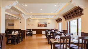 Un restaurante espacioso con suelo de madera, techos altos y una zona central de comedor con mesas y sillas.