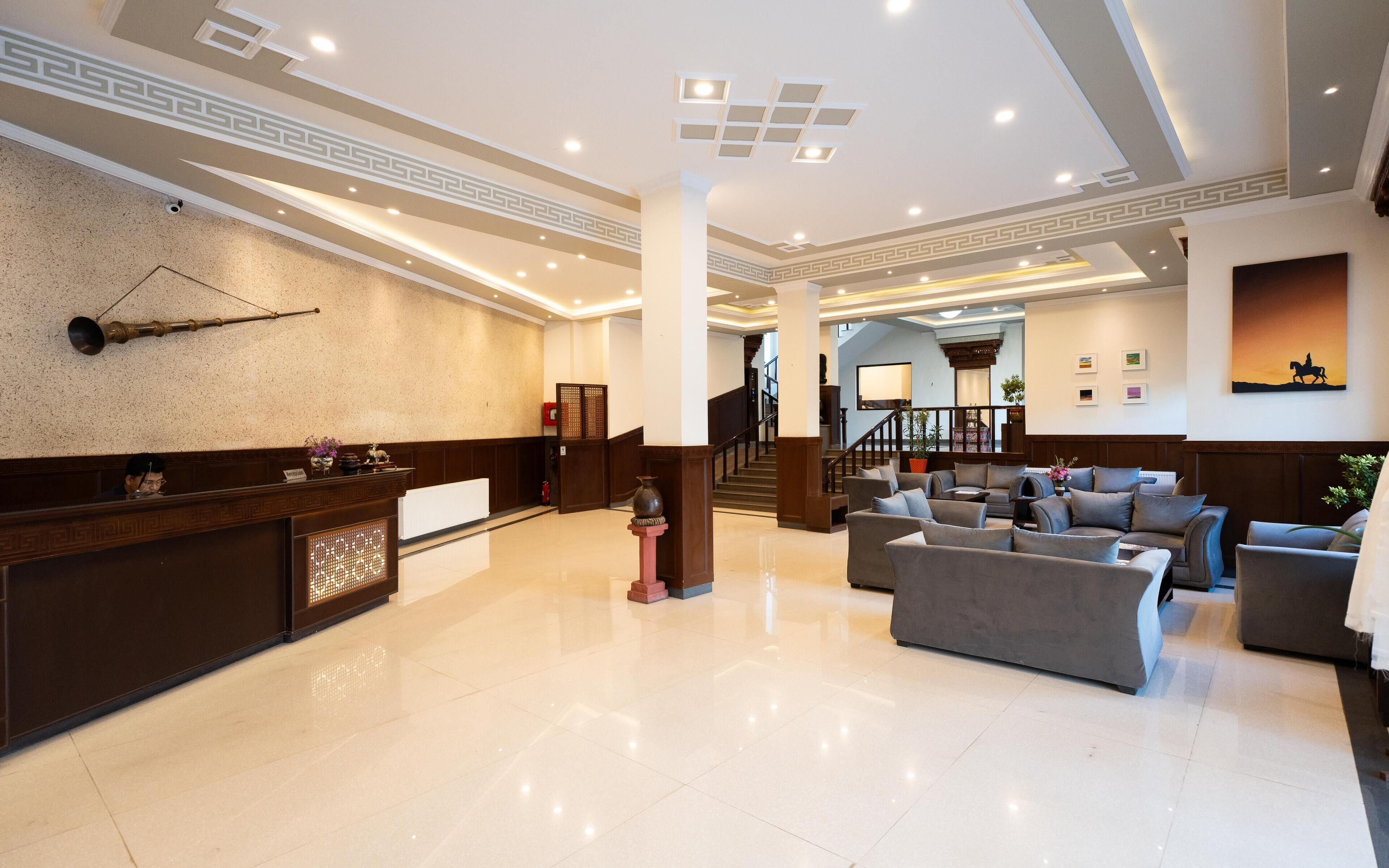 A spacious lobby with a reception desk, seating area, and a staircase leading to upper floors.