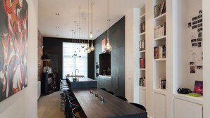 A modern kitchen with a central island, pendant lighting, and a bookshelf filled with books and photos. - Flagey Terrace Design residence (Brussels)