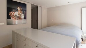 A bedroom with a bed, a dresser, a door, and a wall-mounted picture. - Flagey Terrace Design residence (Brussels)
