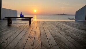 A wooden deck with a bench and a table, overlooking a sunset over the sea. - Secret Pool Villa SEJI (Motobu)