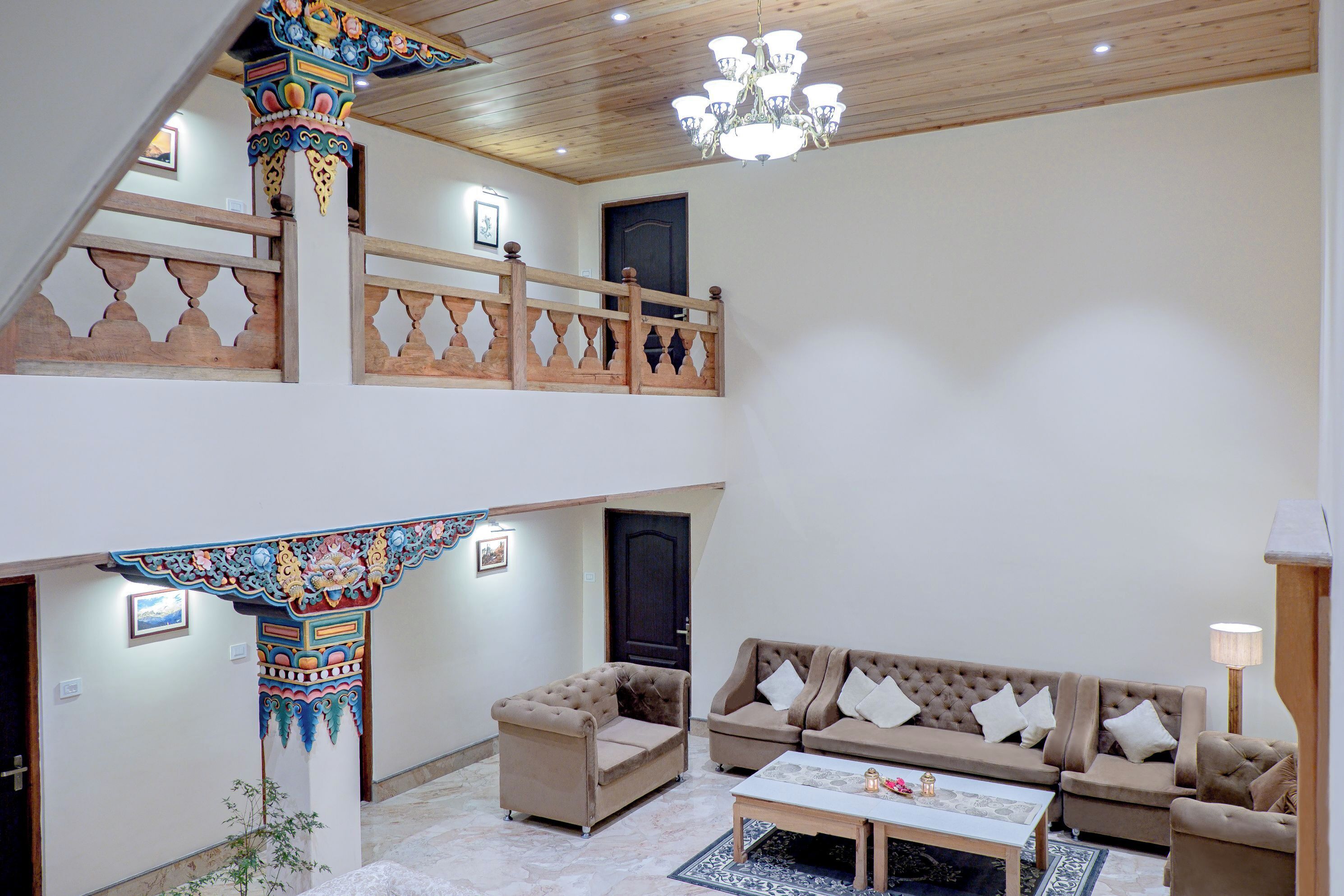 A spacious living area with a high ceiling, a chandelier, a sofa set, and a decorative pillar.