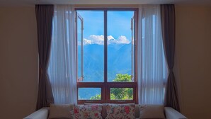 Ein Zimmer mit einer Couch, die zu einem großen Fenster mit Blick auf die Berge blickt.