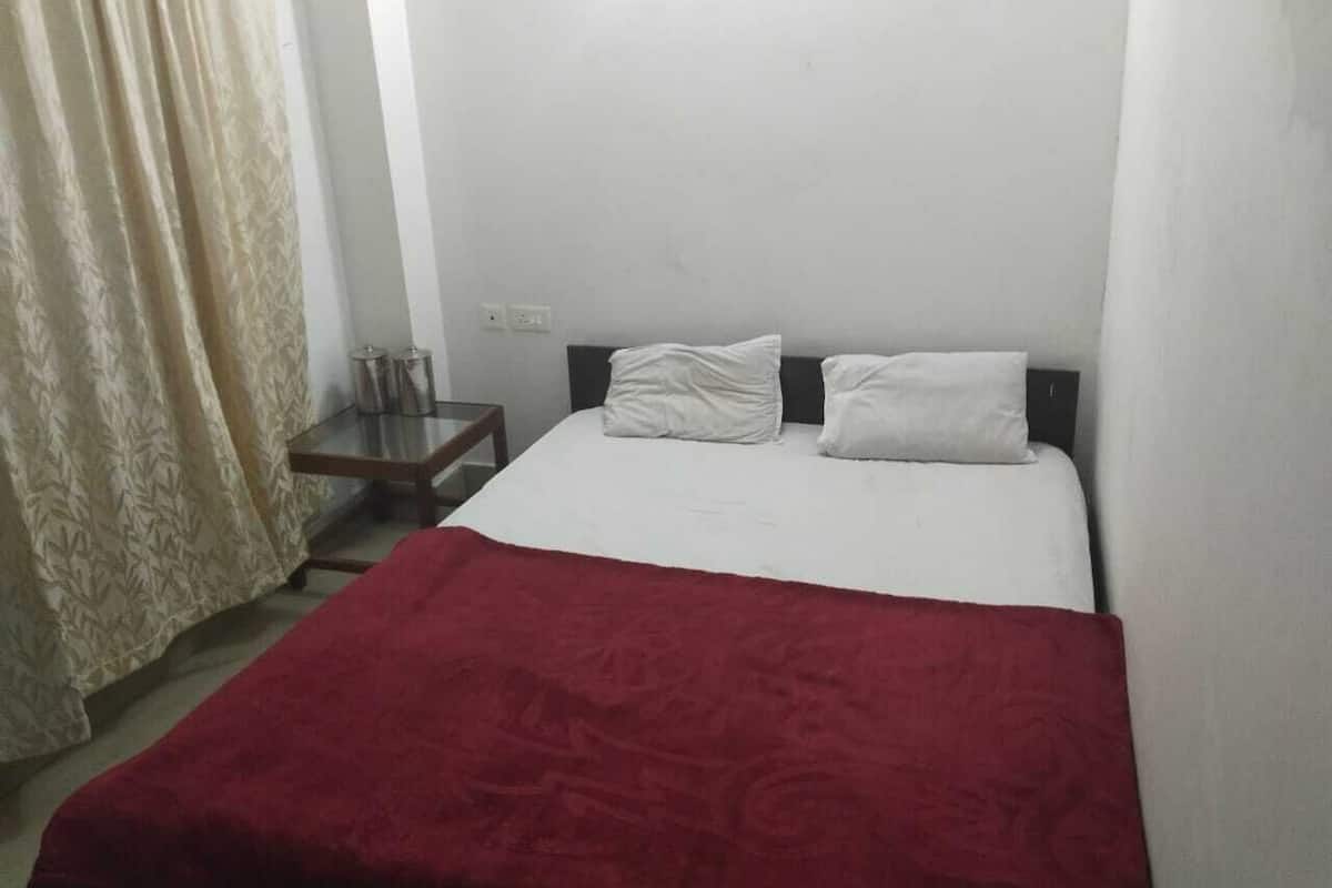 A simple, clean room with a bed, a small table, and a curtain.